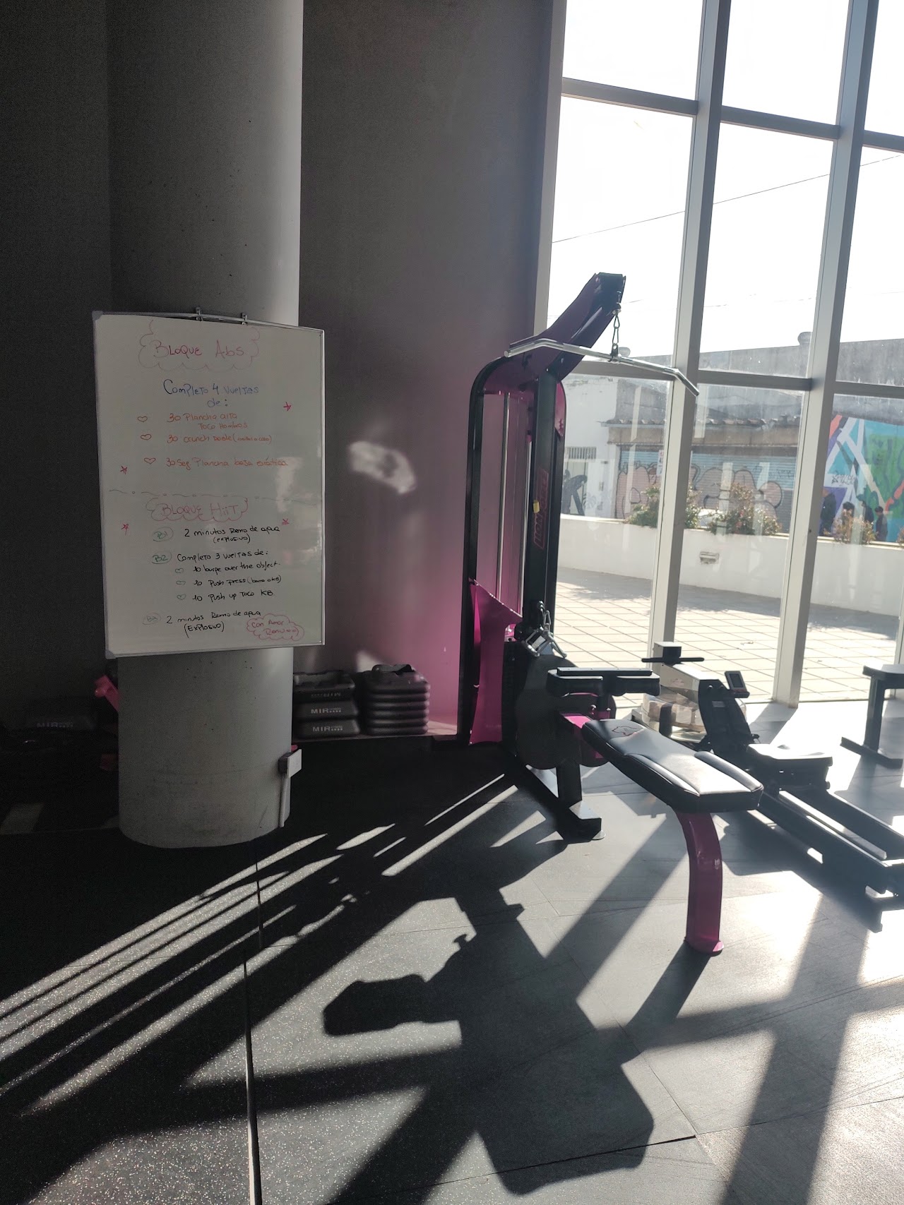 Modern boutique gym interior with custom vibrant magenta pink and matte black weightlifting equipment in Berazategui